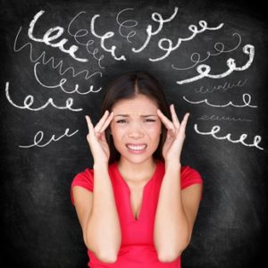 Stress - woman stressed with headache. Female stressed and worried with migraine headache pain. Blackboard concept with young female model on chalkboard black background. Asian Chinese / Caucasian.